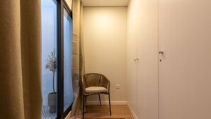 A narrow hallway with a chair, a potted plant, and a wardrobe. - Cozy Apartment only 500m from Douro River | With A/C by Lisbeyond (Vila Nova de Gaia)