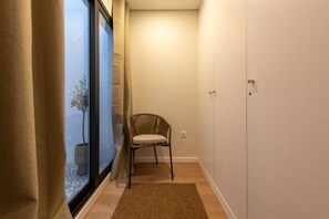 A narrow hallway with a chair, a potted plant, and a wardrobe.
