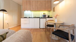 A compact kitchen with white cabinets, a microwave, and a coffee machine. There is a small dining area with a round table and two chairs. - Cozy Apartment only 500m from Douro River | With A/C by Lisbeyond (Vila Nova de Gaia)