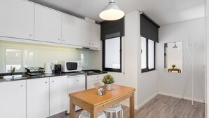A modern kitchen with white cabinets, a wooden dining table, and a pendant light. - Duplex River View Apartment | With A/C by Lisbeyond (Vila Nova de Gaia)