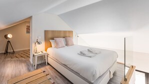 A modern bedroom with a large bed, a nightstand, a lamp, and a view of the sky. - Duplex River View Apartment | With A/C by Lisbeyond (Vila Nova de Gaia)