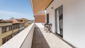 A balcony with a view of neighboring buildings, a table and chairs, and a large window. - Duplex River View Apartment | With A/C by Lisbeyond (Vila Nova de Gaia)