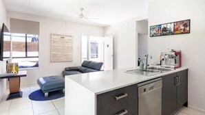 Una cocina moderna con una isla central, un área de comedor con sofá y vistas al exterior.