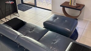 Una sala de estar moderna con un sofá de cuero, un televisor de pantalla plana y una mesita con libros y un control remoto.