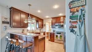 Una cocina moderna con armarios de madera, electrodomésticos de acero inoxidable y una isla central con taburetes de bar.