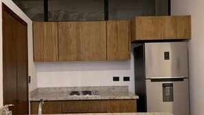 Una cocina moderna con armarios de madera, un refrigerador de acero inoxidable y una encimera de granito.