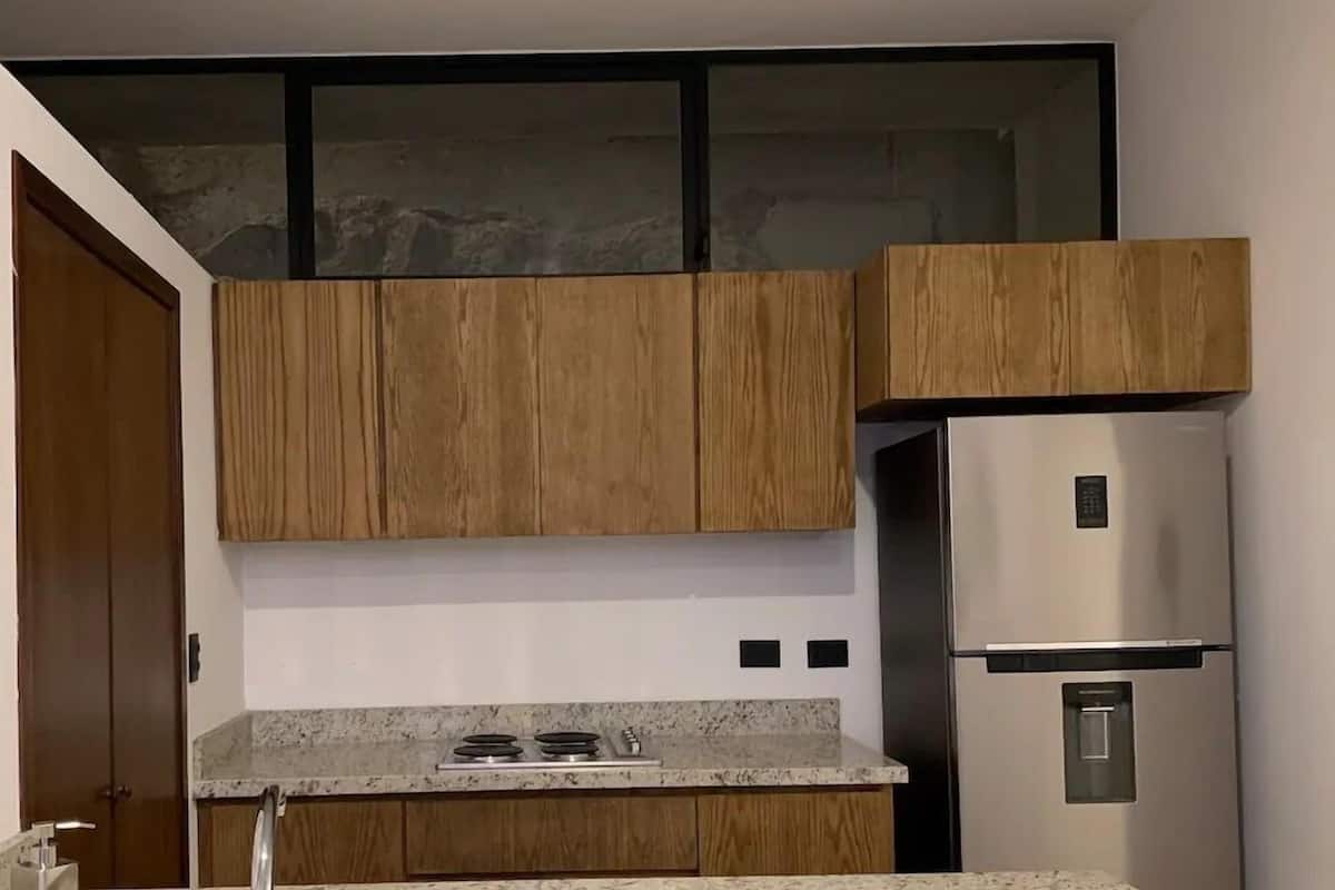 Una cocina moderna con armarios de madera, un refrigerador de acero inoxidable y una encimera de granito.