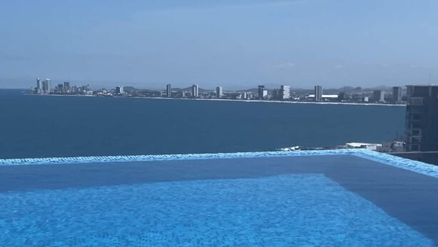 Una piscina infinita con vistas a un horizonte urbano y al océano.