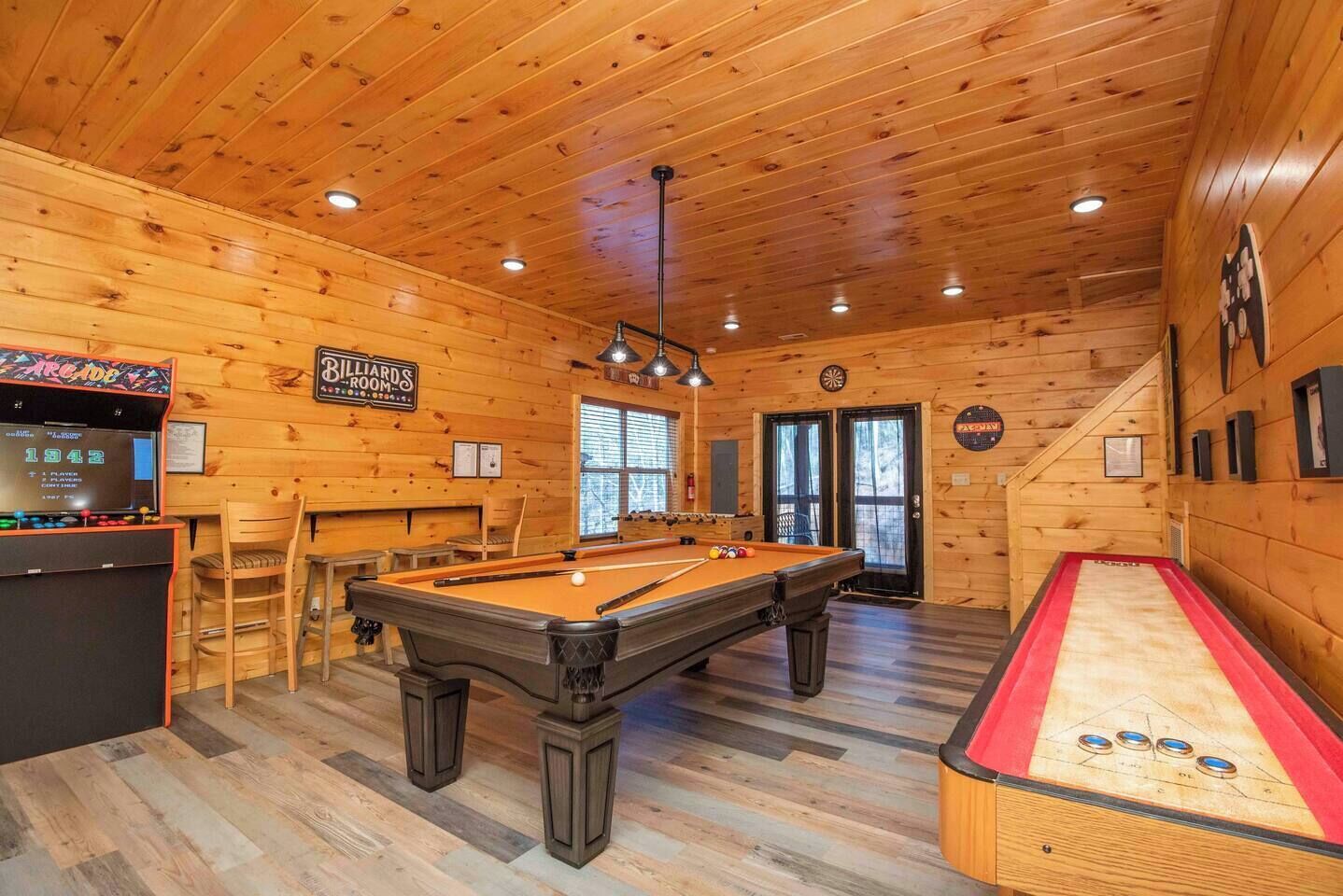 A billiards room with a pool table, a foosball table, and a dartboard.
