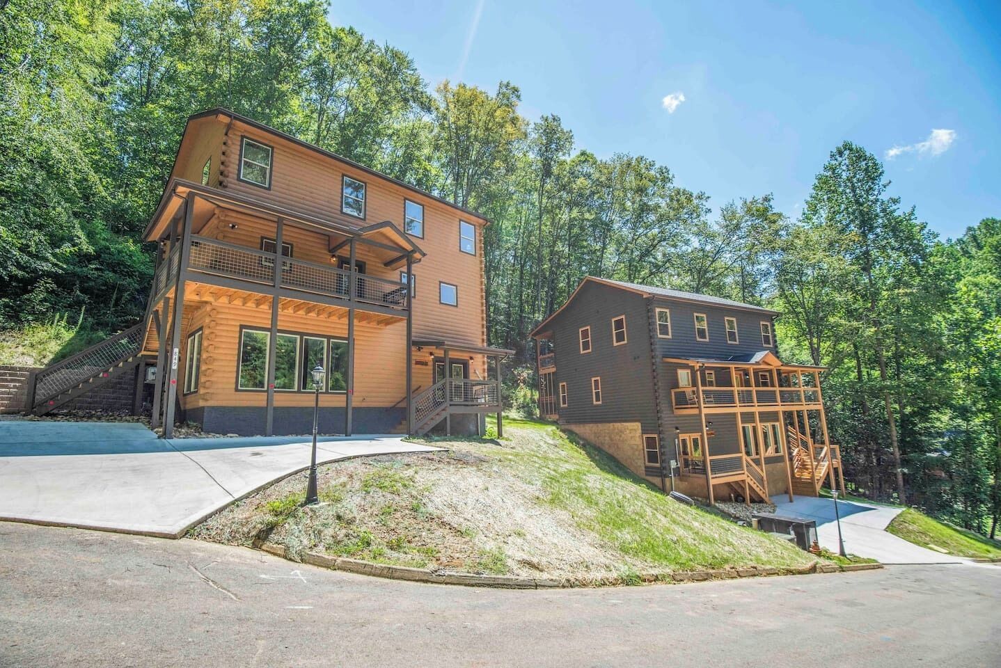 A two-story wooden cabin with a balcony, surrounded by trees.