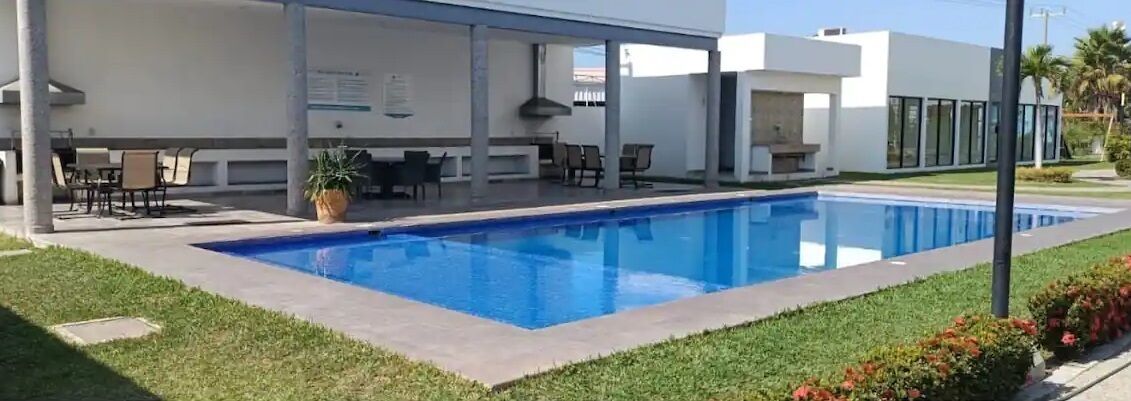 Un edifici modern amb piscina, zona d'estar a l'exterior i terrassa coberta.