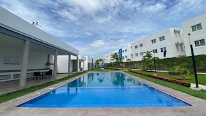A modern hotel with a swimming pool, outdoor seating, and a clear blue sky. - CONDOS AA (Mazatlán)