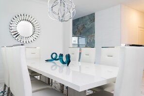 A modern dining area with a white table, chairs, and a decorative mirror. - Blue Heaven - Luxe Ocean Villa - Beach House - Private Pool (Melbourne Beach)
