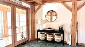 Un intérieur rustique avec des poutres apparentes, un grand miroir, une console surmontée de paniers et une enseigne indiquant « Lake of Bays ».