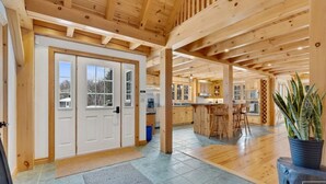 Un intérieur spacieux en bois, avec une grande cuisine ouverte, des poutres apparentes au plafond et une plante en pot.