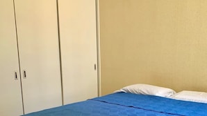 A bedroom with a bed, a wardrobe, and a plain wall. - Condos FRP (Mazatlán)
