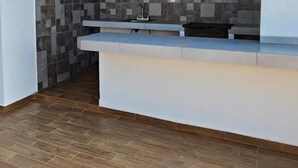 A modern kitchen with a tiled backsplash, a countertop, and a wooden floor. - Condos FRP (Mazatlán)