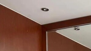 A modern living room with a grey sectional sofa, wooden panel walls, and a recessed ceiling light. - Condos FRP (Mazatlán)
