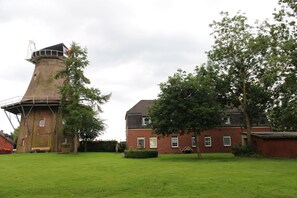 Un moulin à vent traditionnel, avec un bâtiment en briques situé à côté.