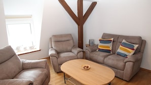 A living room with two sofas, a coffee table, and a wooden accent wall.