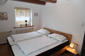 Une chambre avec deux lits, une fenêtre donnant sur un immeuble en briques et une table de chevet avec une lampe.