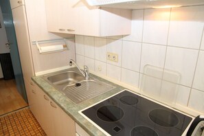 A kitchen with a stainless steel sink, a built-in stove with four burners, and a small countertop.