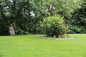 A statue in a garden with a well-maintained lawn and a variety of plants.