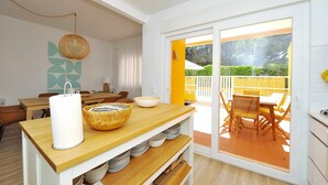 A modern kitchen with a wooden countertop, a hanging light fixture, and a view of the outdoor patio. - Tropical Pool View Cascais - Checkinhome (Cascais)