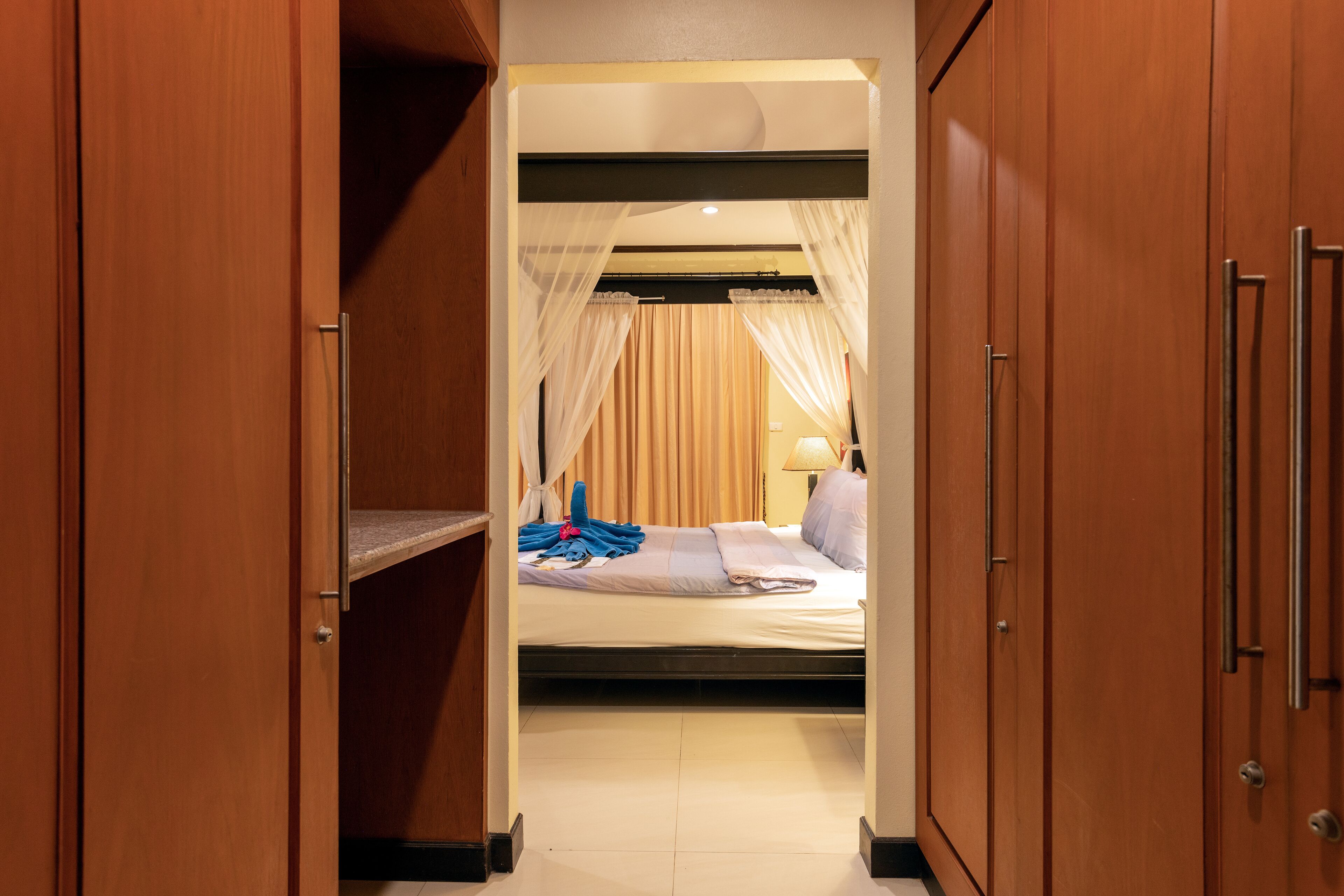 A hotel room with a bed, a bedside table, and a wardrobe.