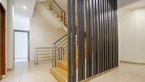 A modern interior with a staircase, a metal railing, and a decorative panel. - TwoSpaces Living at Maximus Inn (Palembang)