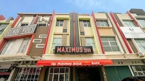 A hotel named MAXIMUS INN with a red and white awning. - TwoSpaces Living at Maximus Inn (Palembang)