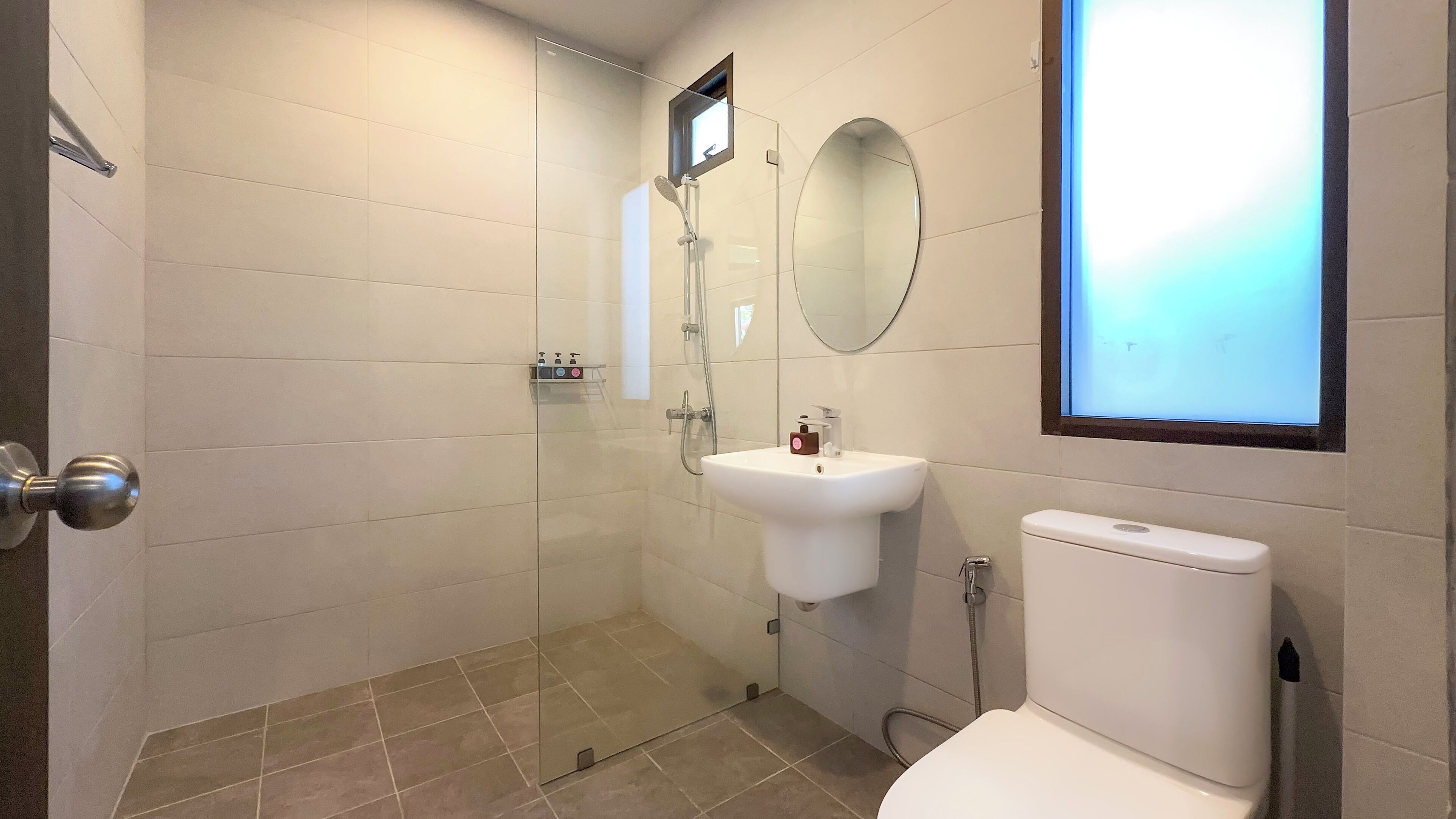 Ein Badezimmer mit Duschkabine aus Glas, Waschbecken mit Spiegel darüber und Toilette.