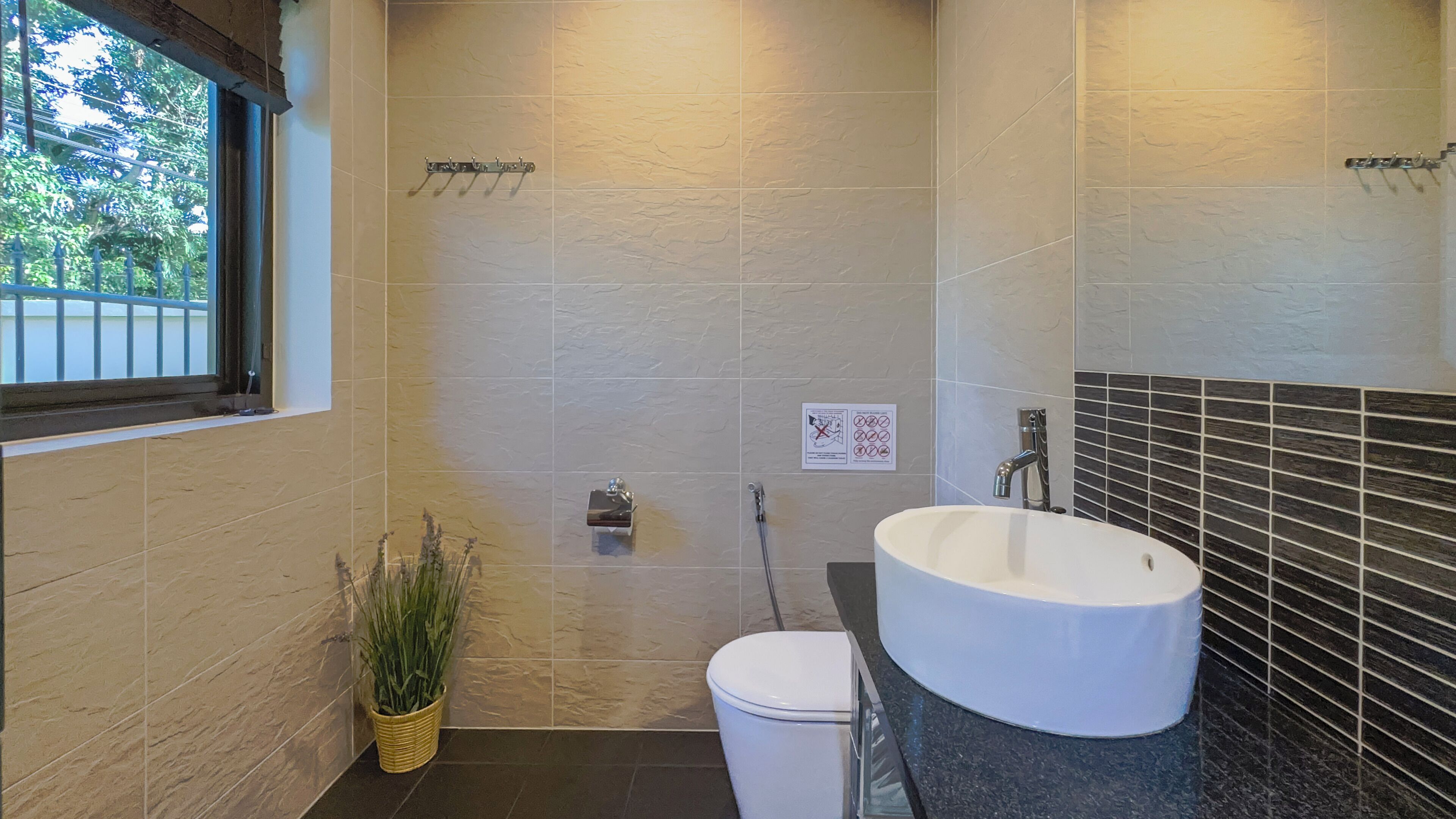 A bathroom with a white toilet, a sink with a black countertop, and a shower area.