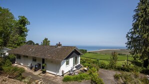 A white house with a tiled roof, a small porch, and a view of the sea. - Gapperies, West Porlock (Porlock Weir)