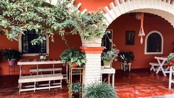 Relax in a charming outdoor seating area with brick archway, wooden benches, and lush greenery.