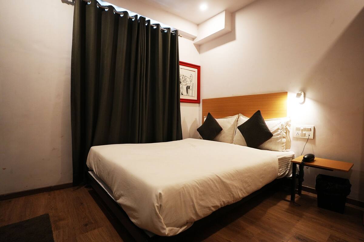 A neatly made bed with a wooden headboard, a nightstand with a lamp, and a picture frame on the wall.