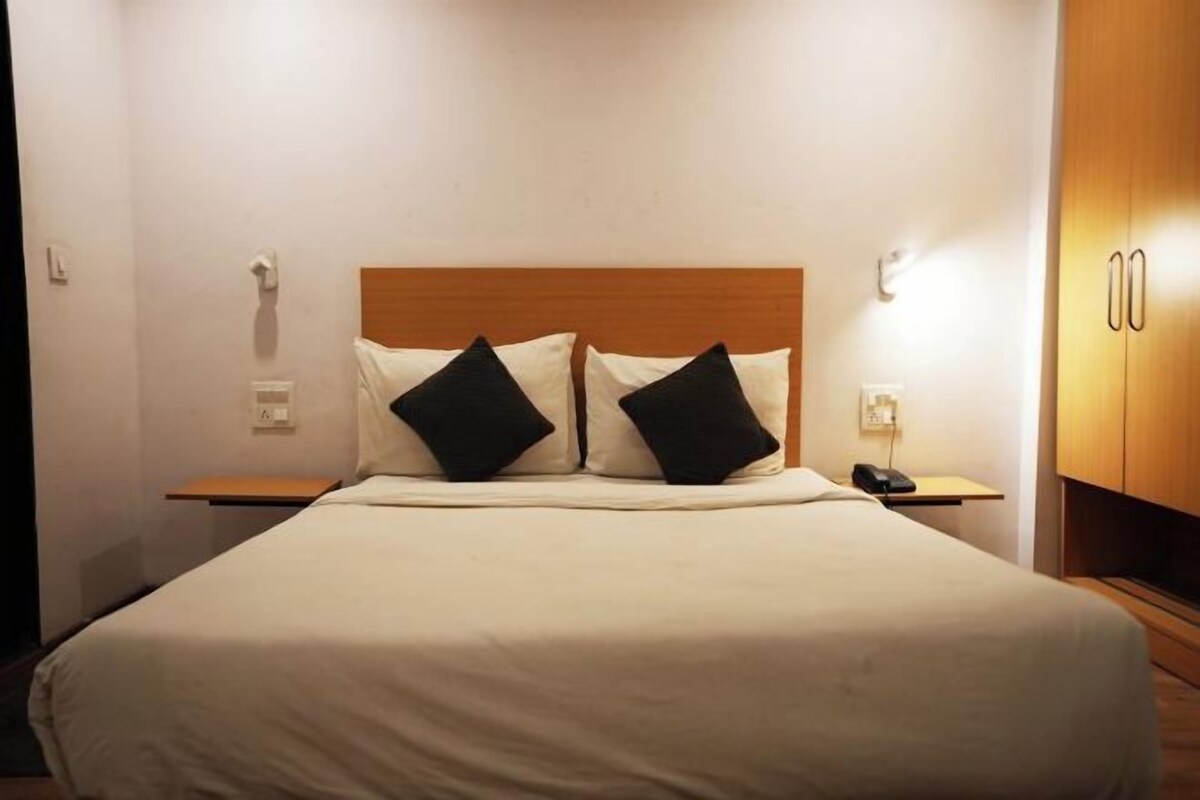 A hotel room with a large bed, two bedside tables, a wooden headboard, and a wooden wardrobe.