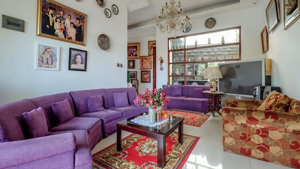 Una sala de estar con sofás morados, un televisor y objetos decorativos en las paredes.