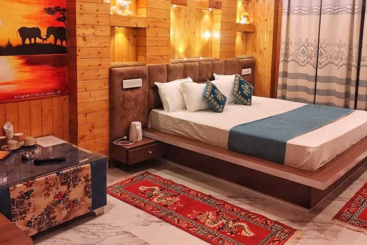 Une pièce en bois avec un lit, une table de chevet, une table recouverte d’une nappe à motifs floraux et une affiche accrochée au mur.