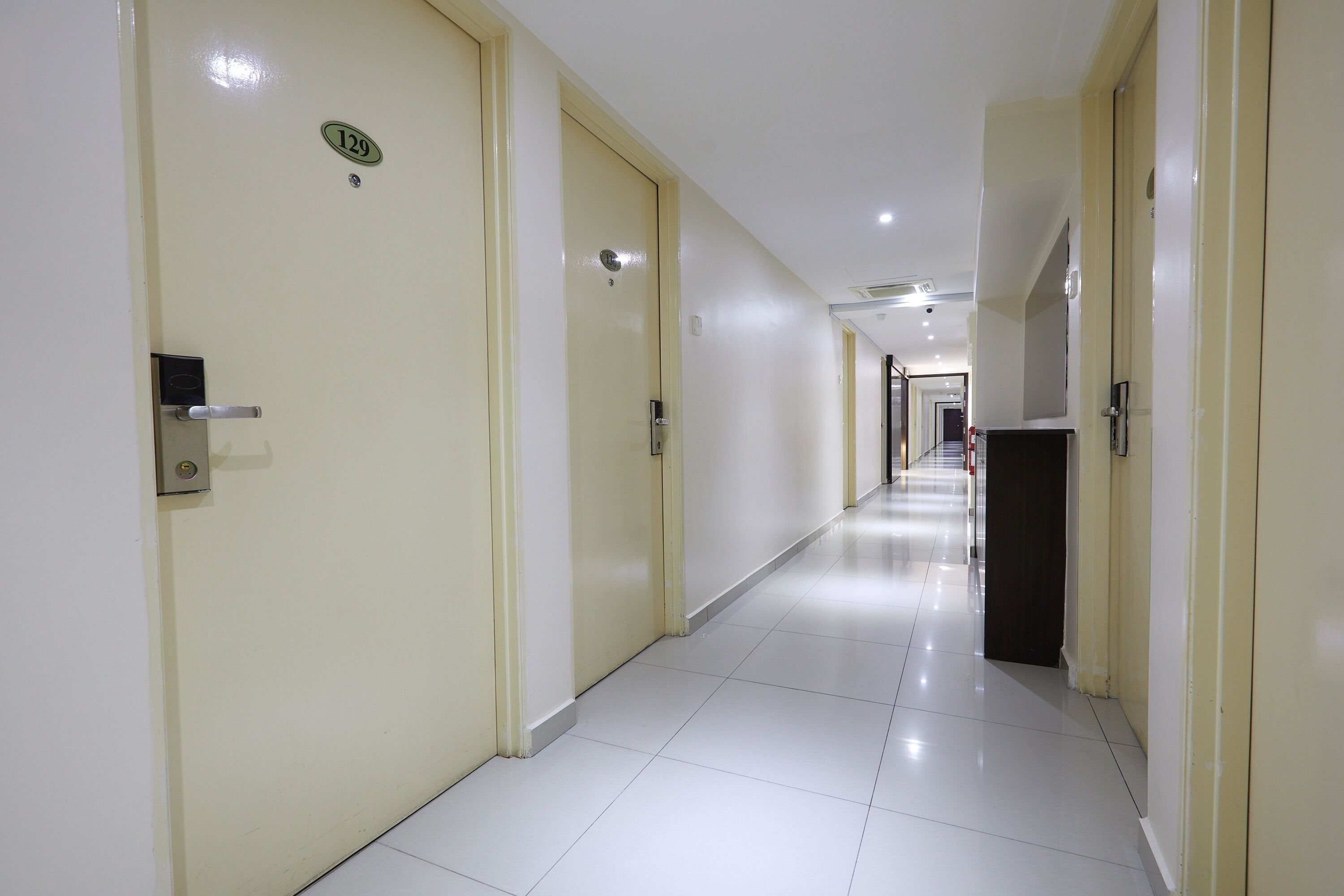 A hotel corridor with doors numbered 129 and 130, leading to rooms.