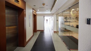 A modern hotel corridor with an elevator, a reception area, and a glass wall with a moon and stars design. - Sungold Inn (Kuala Lumpur)