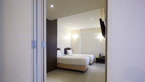 A hotel room with two beds, a nightstand, a wall-mounted TV, and a bathroom visible through an open door. - Sungold Inn (Kuala Lumpur)