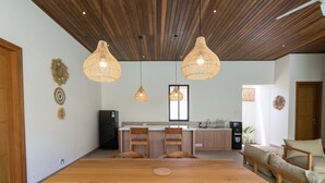 Eine moderne Küche mit Holzboden, Pendelleuchten und einem Essbereich mit einem Holztisch und Stühlen.