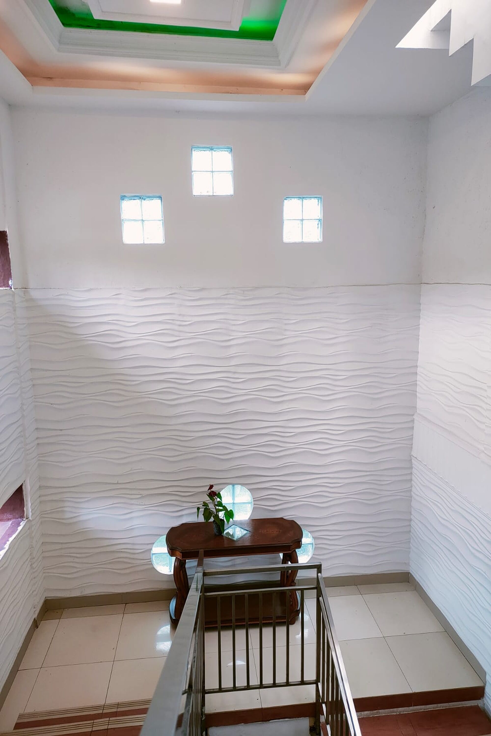 Una habitación con pared texturizada, una pequeña mesa con una planta y una escalera.