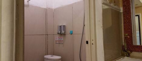 Een kleine badkamer met tegels, een toilet, een douche en een handdoekhouder.
