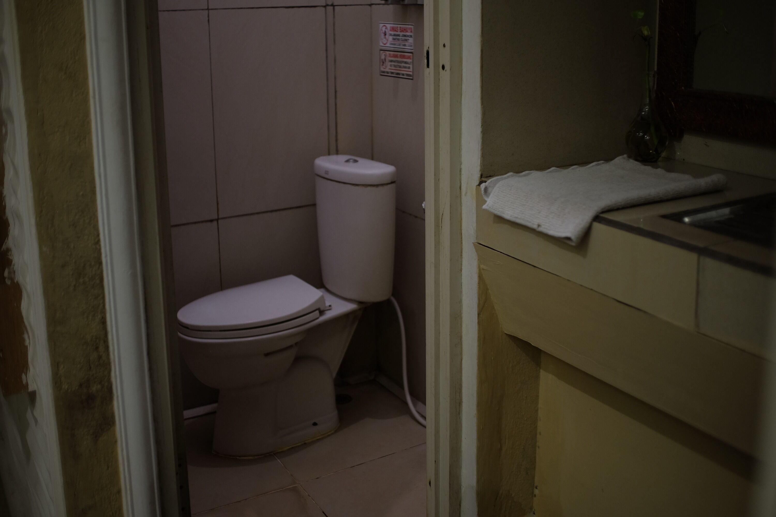 A small, dimly lit bathroom with a toilet and a sink.
