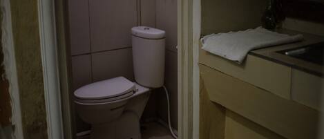 A small, dimly lit bathroom with a toilet and a sink.