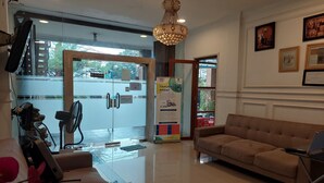 A reception area with a sofa, a chandelier, a fan, and a poster.