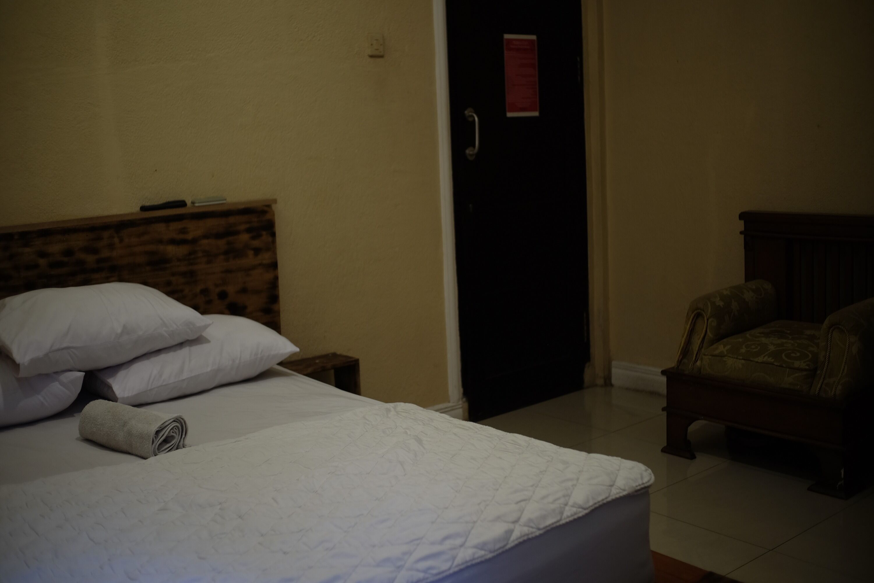A hotel room with a bed, a chair, and a door.