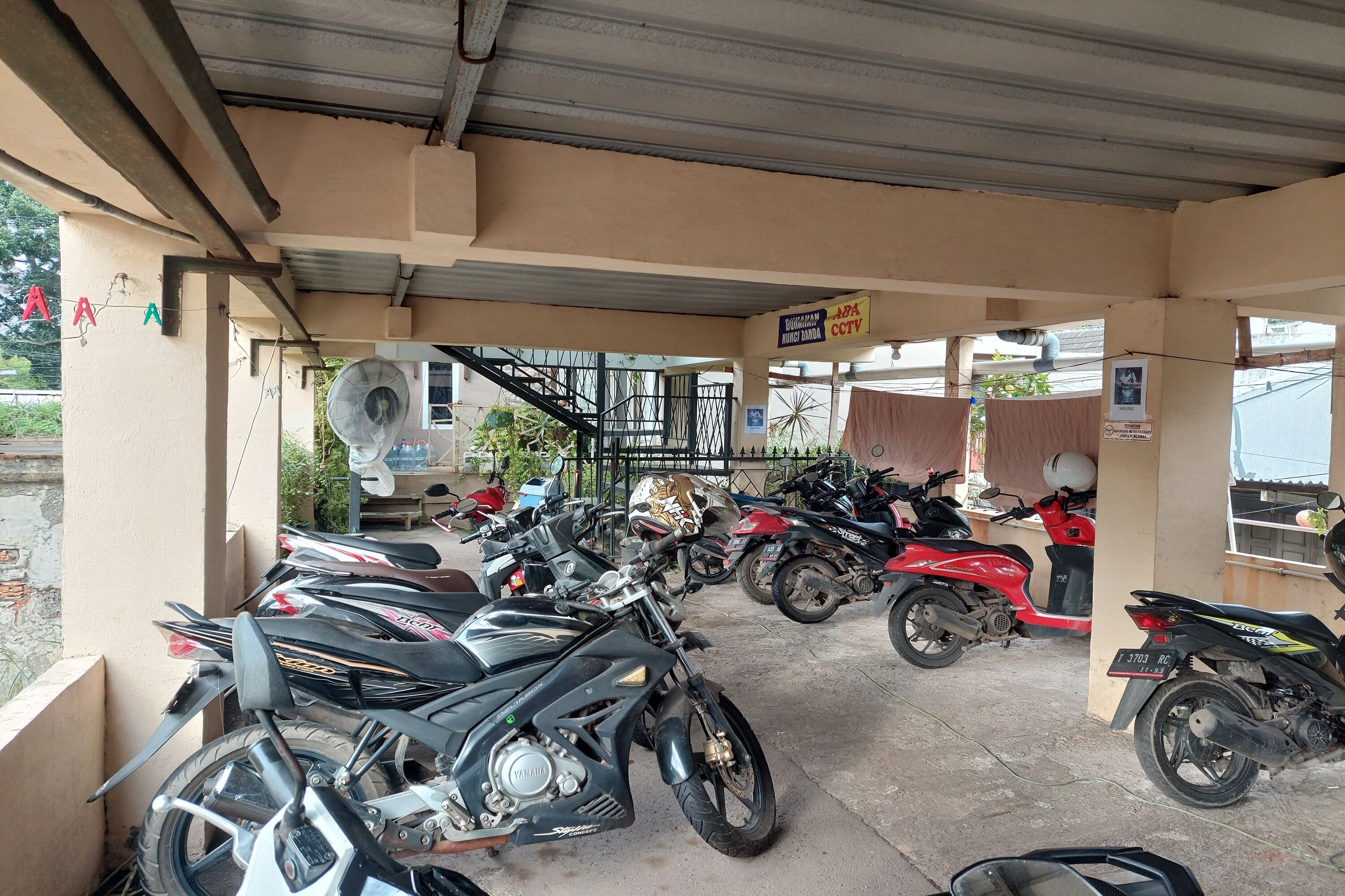 A covered parking area with multiple motorcycles parked.